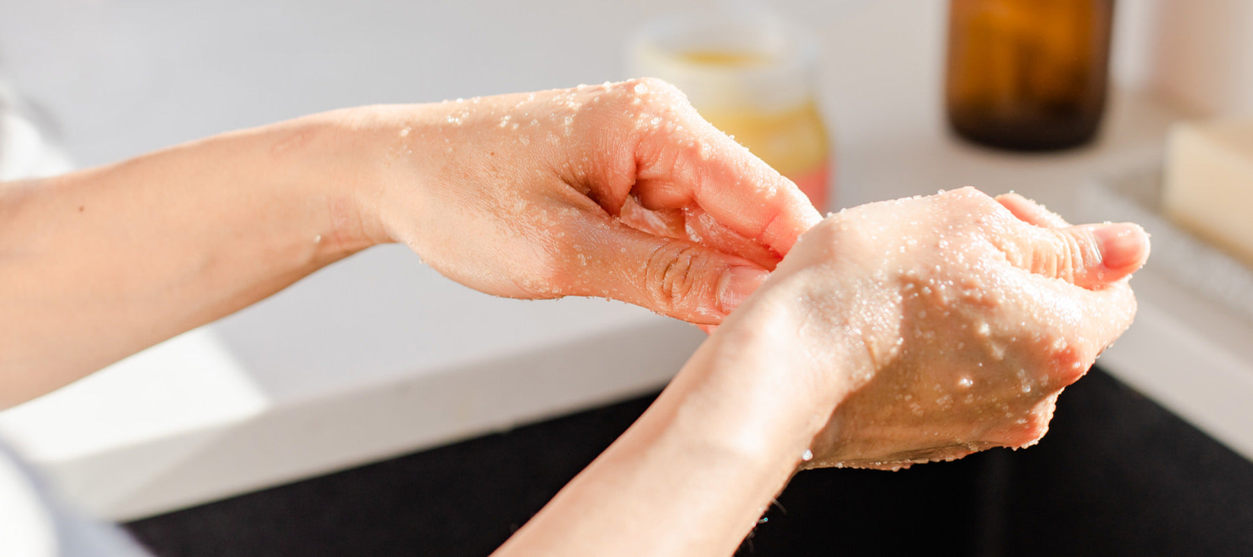 Hands over a sink exfoliating with Rocky Mountain Soap Company body scrub. 