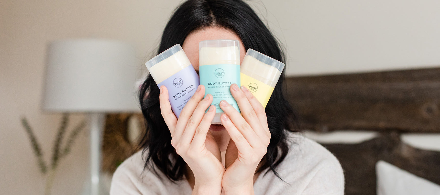 Woman holding up three all natural organic Rocky Mountain Soap Company body butters made with local Canadian beeswax.