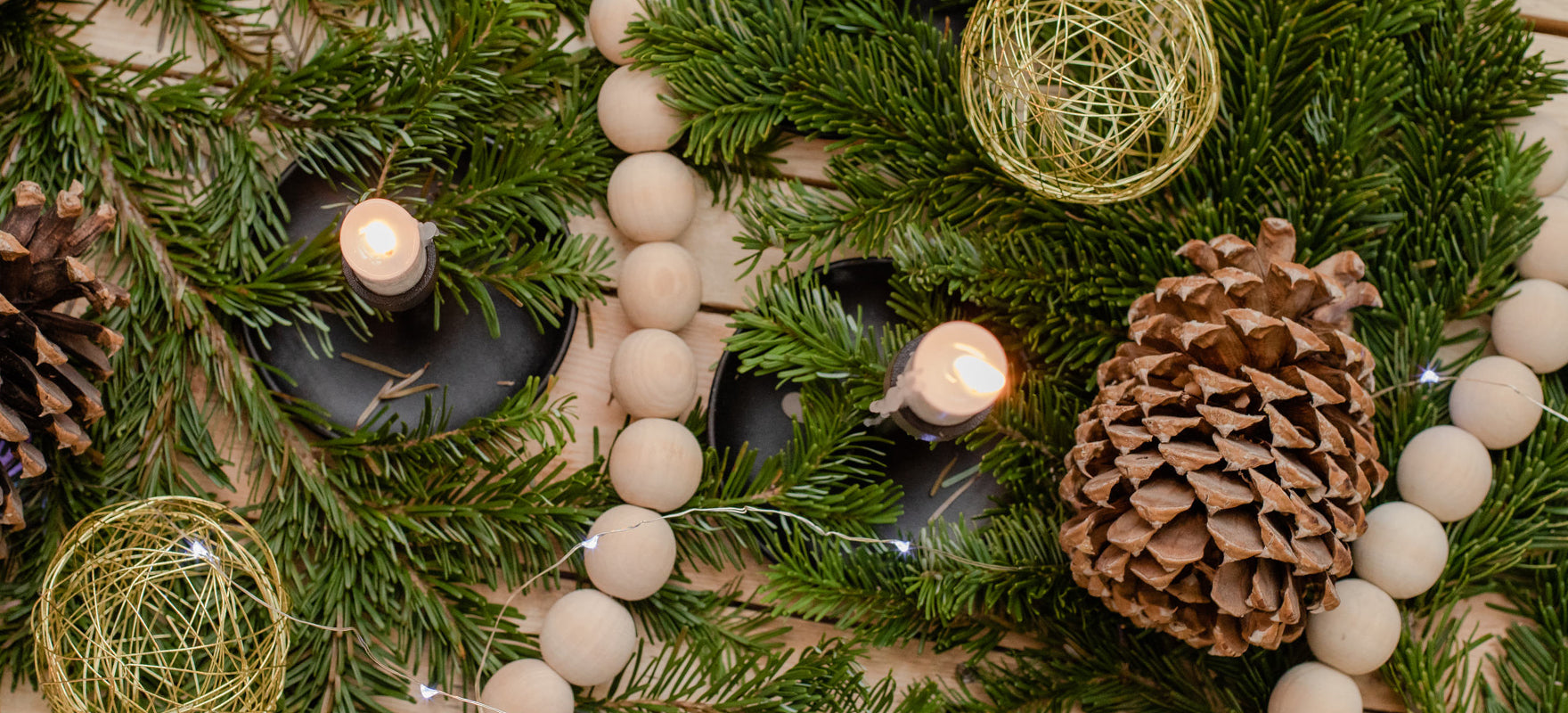 Pieces of spruce, a pine cone, and candles are holiday decorations for this header image on the blog post about what sparks joy for Rocky Mountain Soap Company employees around the holidays. 