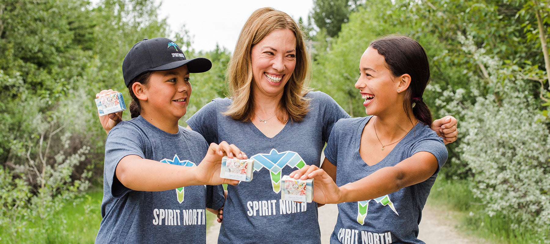 Image of Beckie Scott and two children from the Spirit North program holding the Spirit North Natural bar soap. 