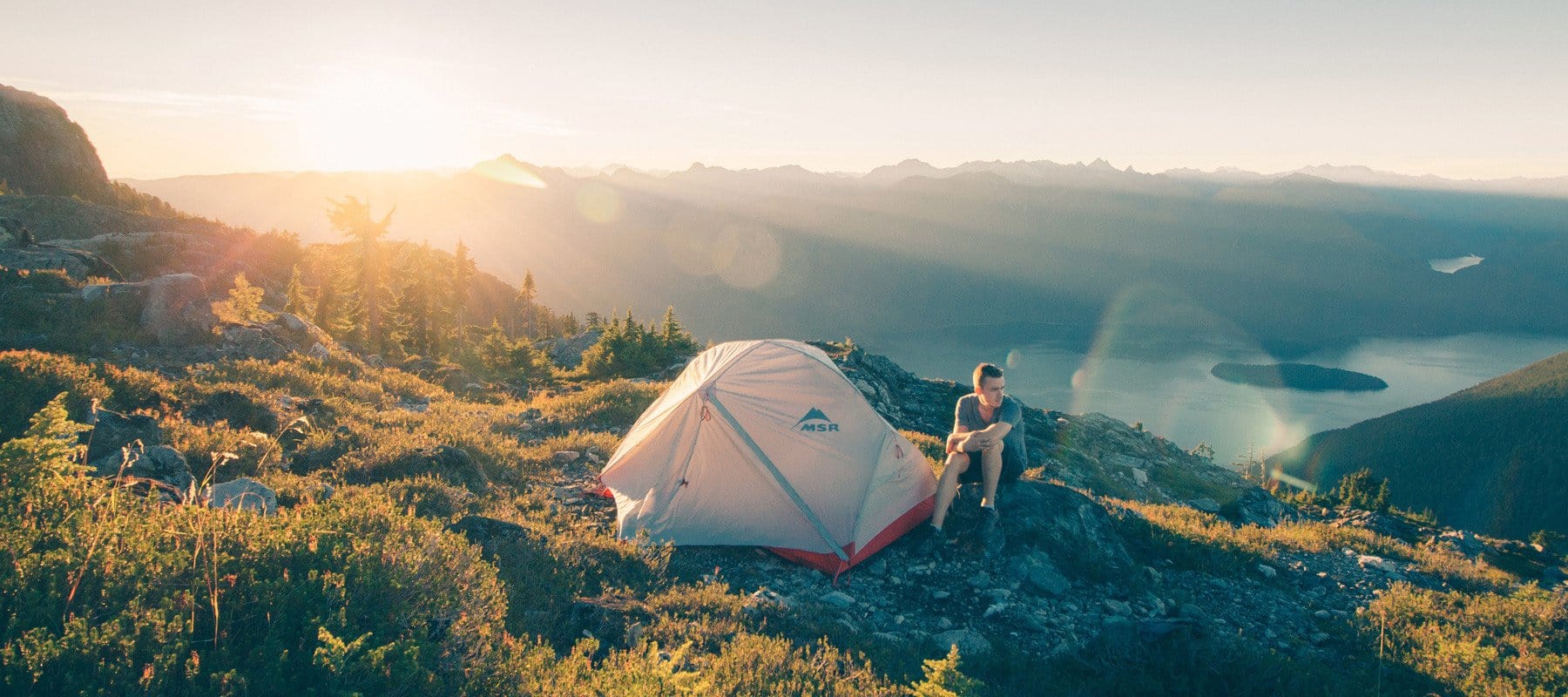 Person camping on a mountain by a lake