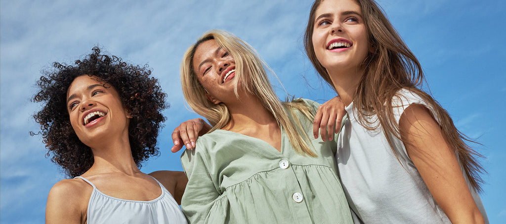 Three women standing next to each other with blue sky in the background.