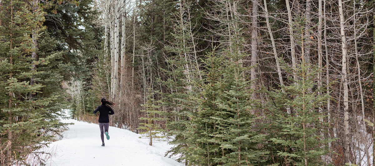 Woman running through the woods with snow.