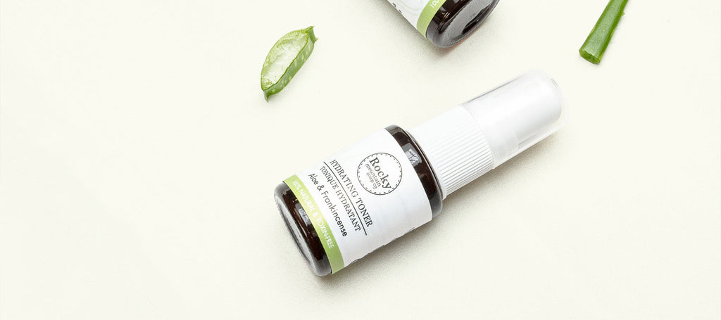 Small bottle of Rocky Mountain Soap Company toner lying on its side with slices of fresh aloe vera plant.