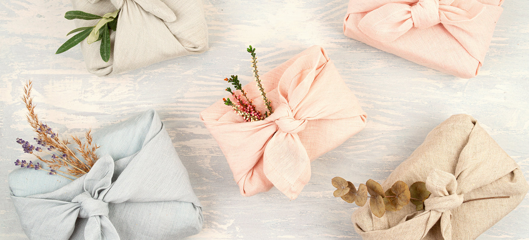 Five multicoloured cloths are artfully wrapped around gifts as a way to reduce landfill waste around the holidays from excess gift wrapping. These furoshiki wraps are an eco-friendly gift wrapping idea. 