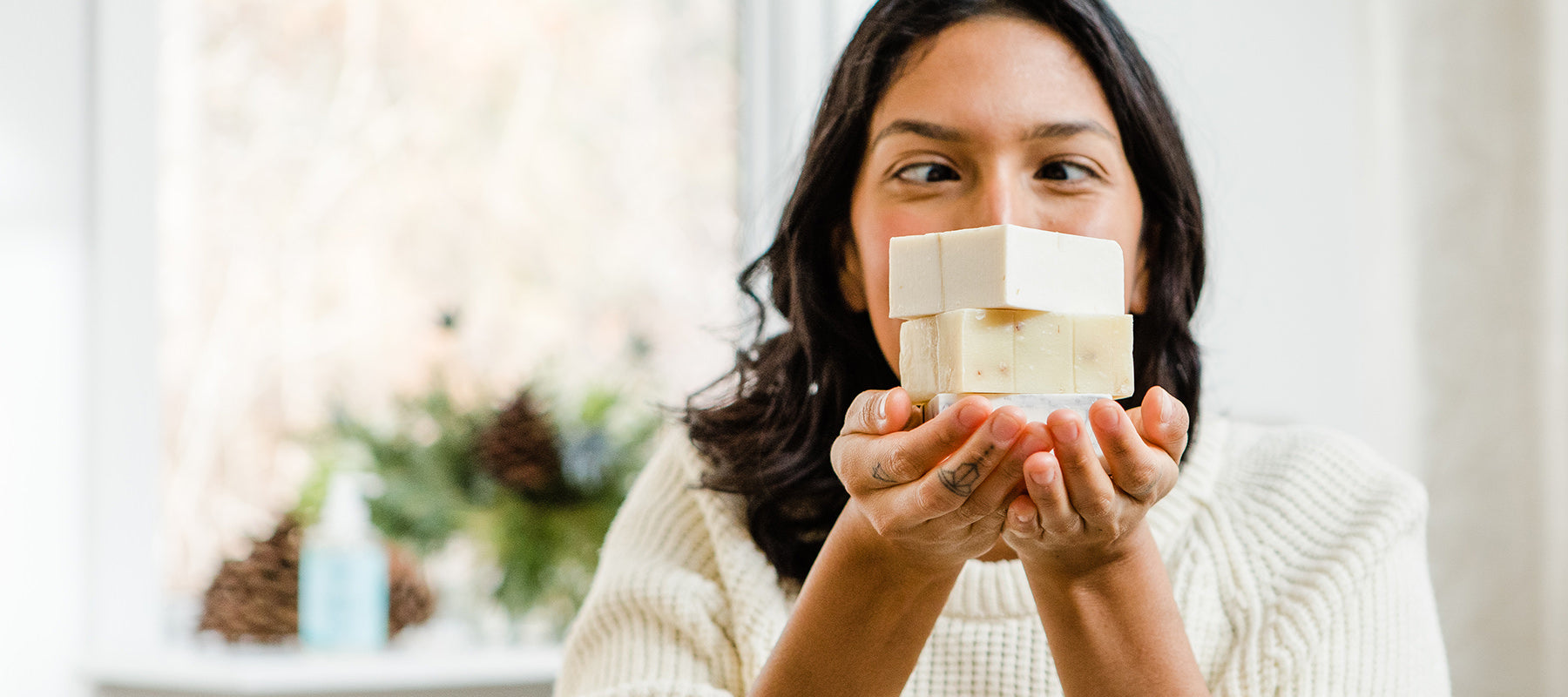 Image of a woman holding a stack of natural bar soap from Rocky Mountain Soap Company 