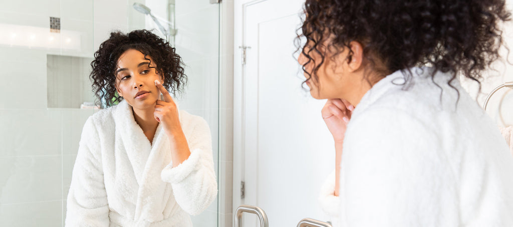 image of women using natural face cream looking in the mirror.