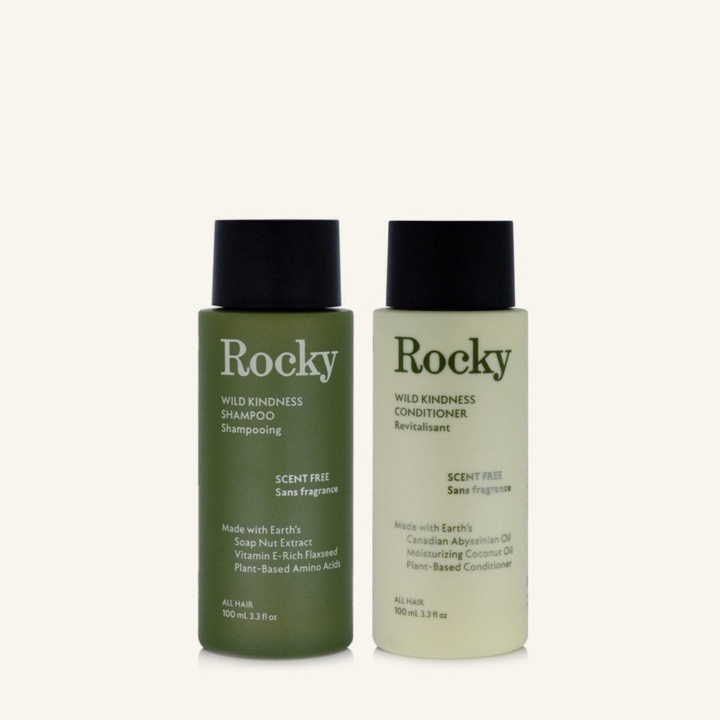 Two 90ml bottles of Rocky Wild Kindness Shampoo and Conditioner in scent free for normal hair, featuring a olive green bottles with black caps, centered on a light cream background.