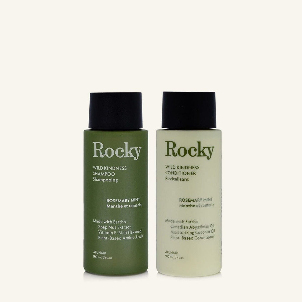 Two 90ml bottles of Rocky Wild Kindness Shampoo and Conditioner in rosemary mint for normal hair, featuring a olive green bottles with black caps, centered on a light cream background.