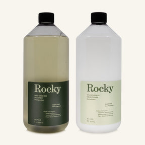 Two 1L bottles of Rocky Wild Kindness Shampoo and Conditioner in scent free for normal hair, centered on a light cream background.