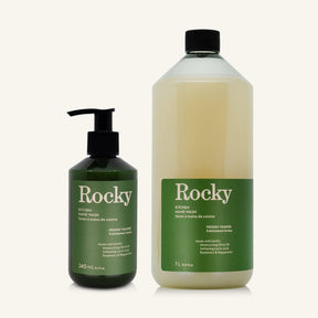 Two bottles of Rocky Kitchen Hand Wash, one in a dark green pump bottle and one in a clear plastic bottle with a black cap, both featuring green labels, on a light cream background.