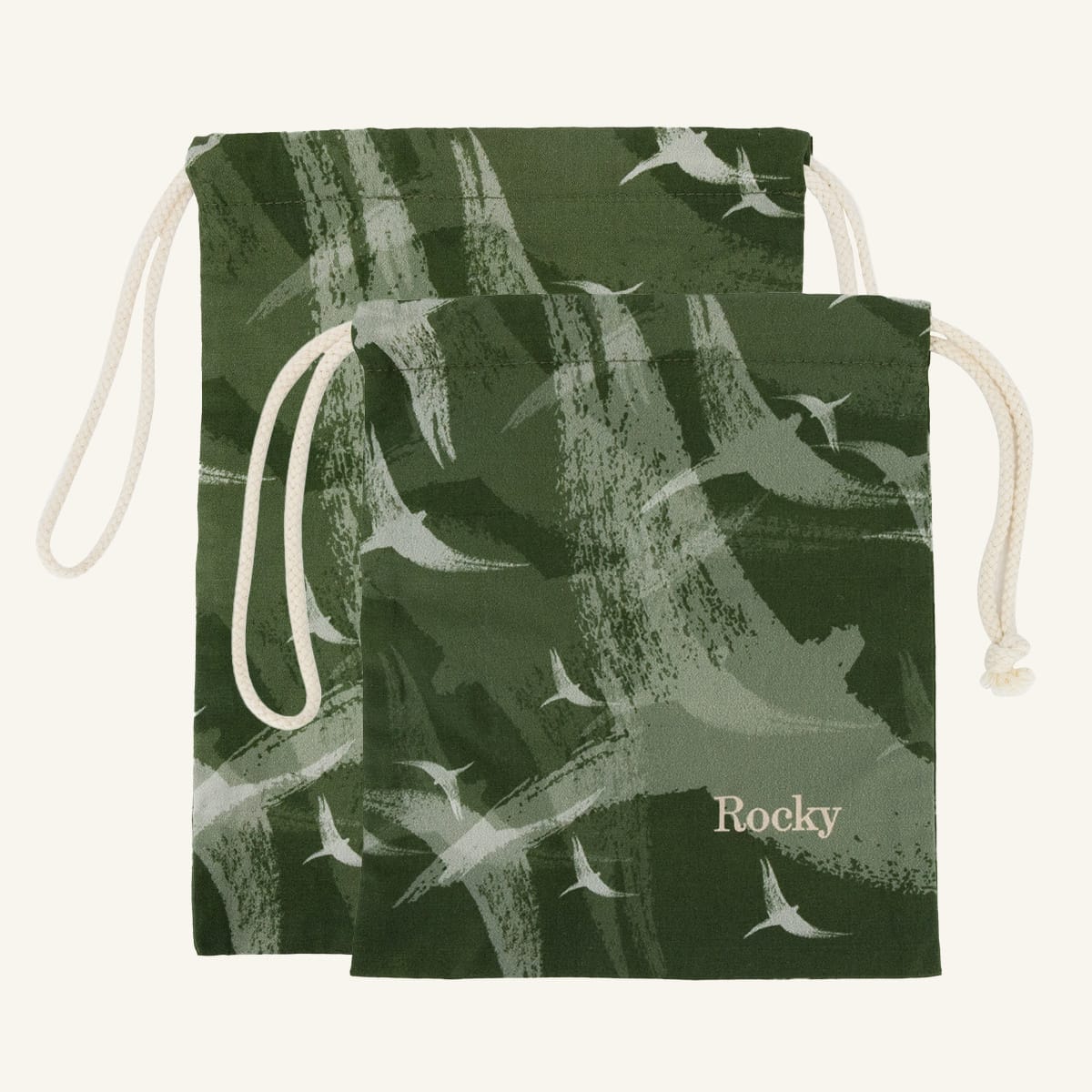 Large and small green drawstring bags with bird pattern and 'Rocky' branding on a white background