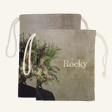 Large and small drawstring bags with floral design and 'Rocky' branding on a beige background