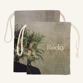 Large and small drawstring bags with floral design and 'Rocky' branding on a beige background