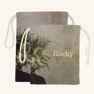 Large and small drawstring bags with floral design and 'Rocky' branding on a beige background
