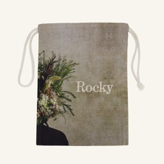 Large drawstring bag with floral design and 'Rocky' branding on a beige background
