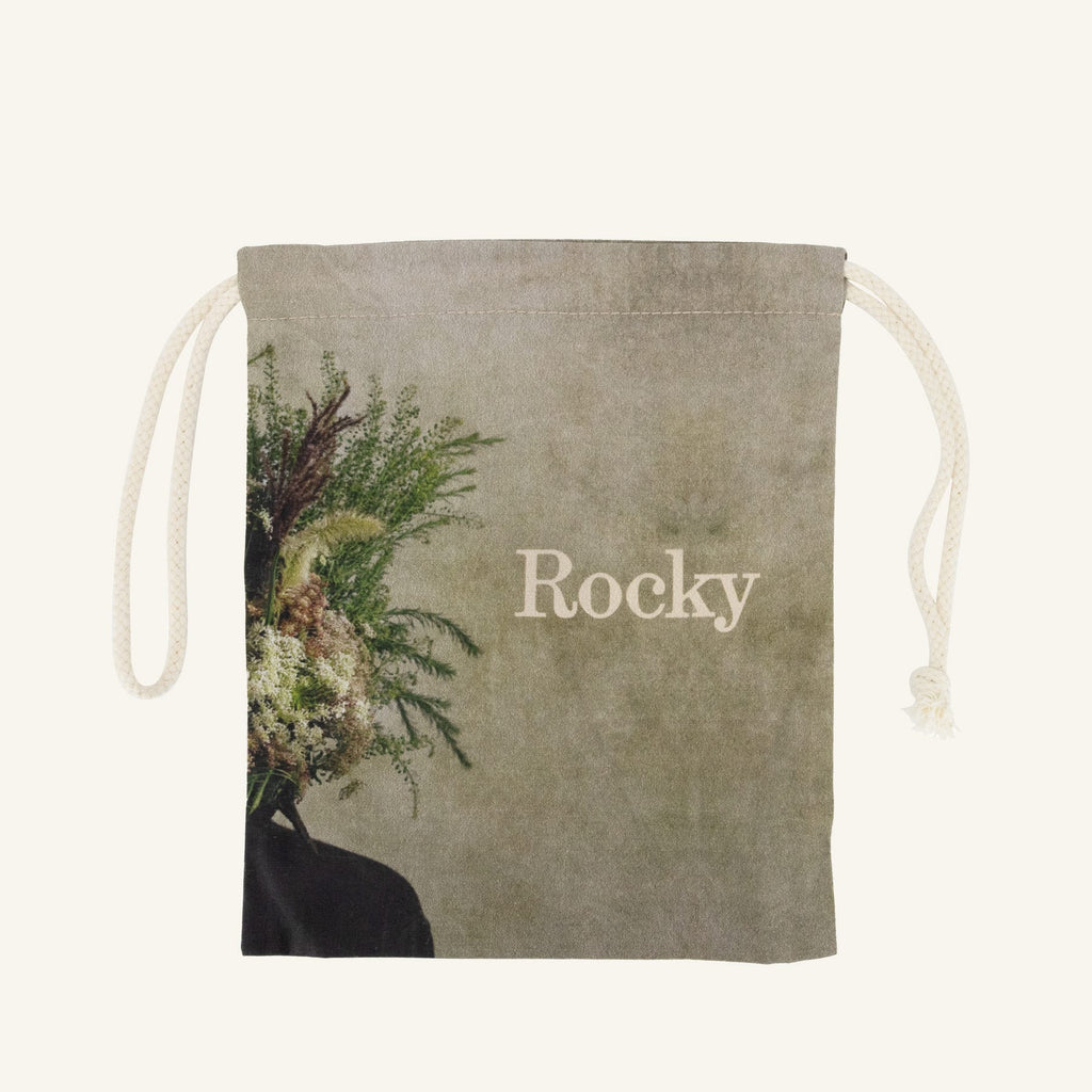 Small drawstring bag with floral design and 'Rocky' branding on a beige background