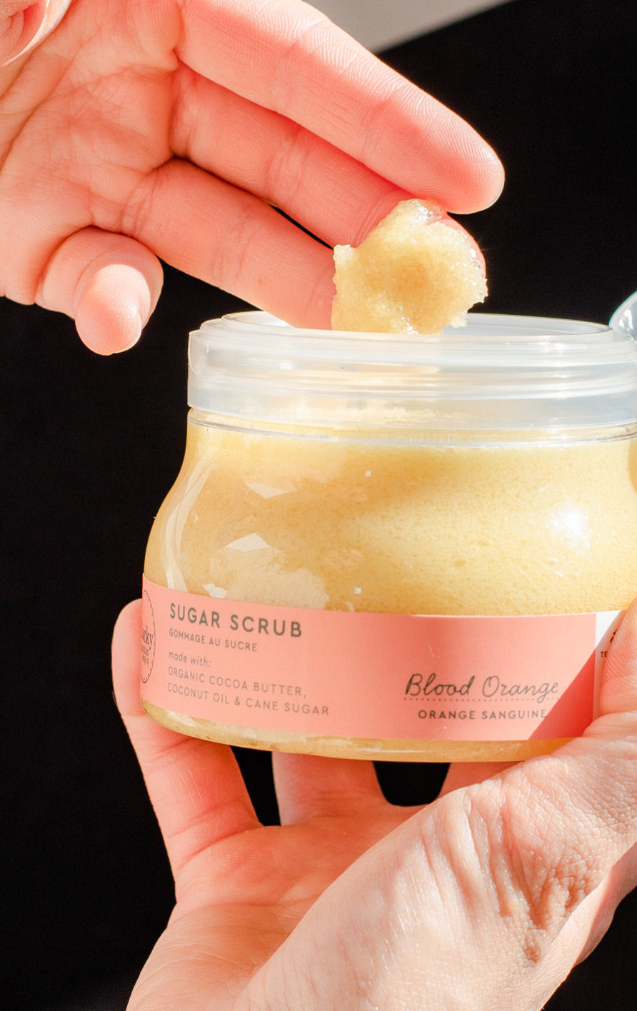 hands holding a container of sugar scrub