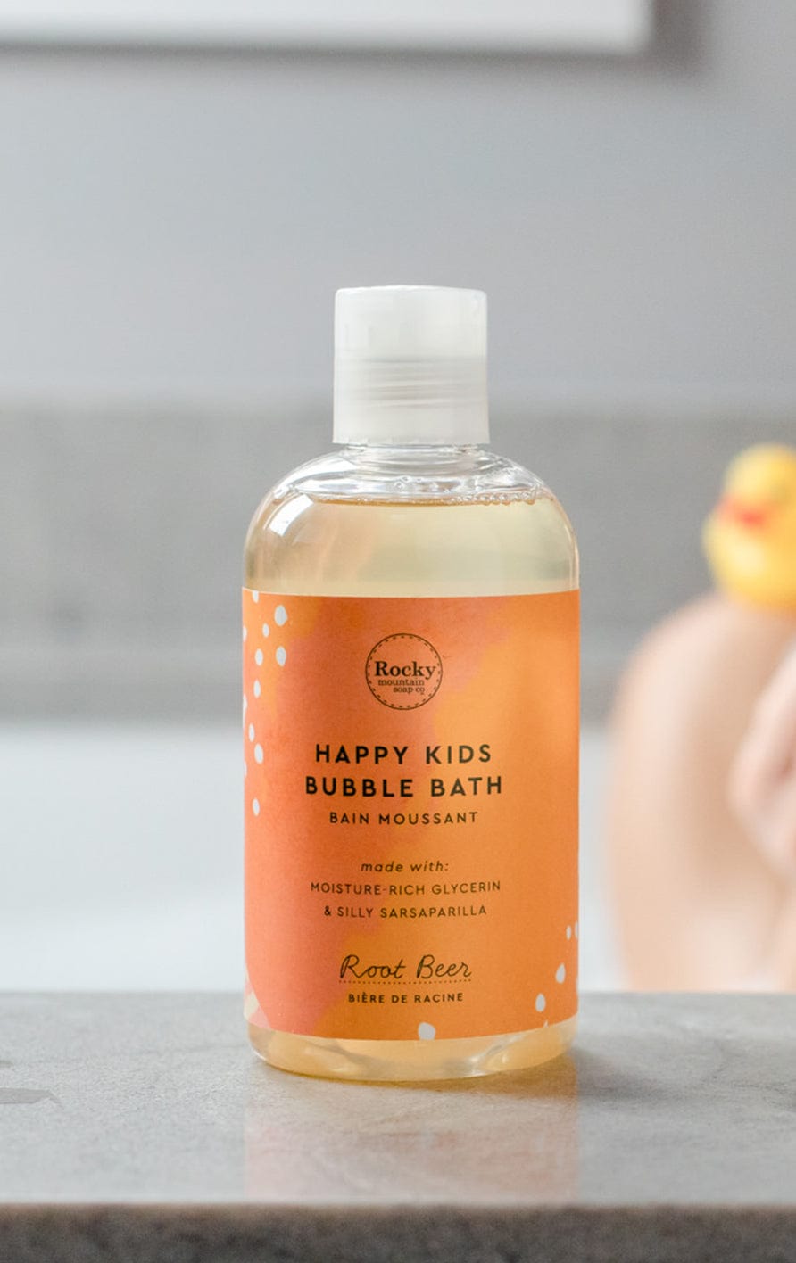 a bottle of happy kids bubble bath resting on the edge of a bathtub
