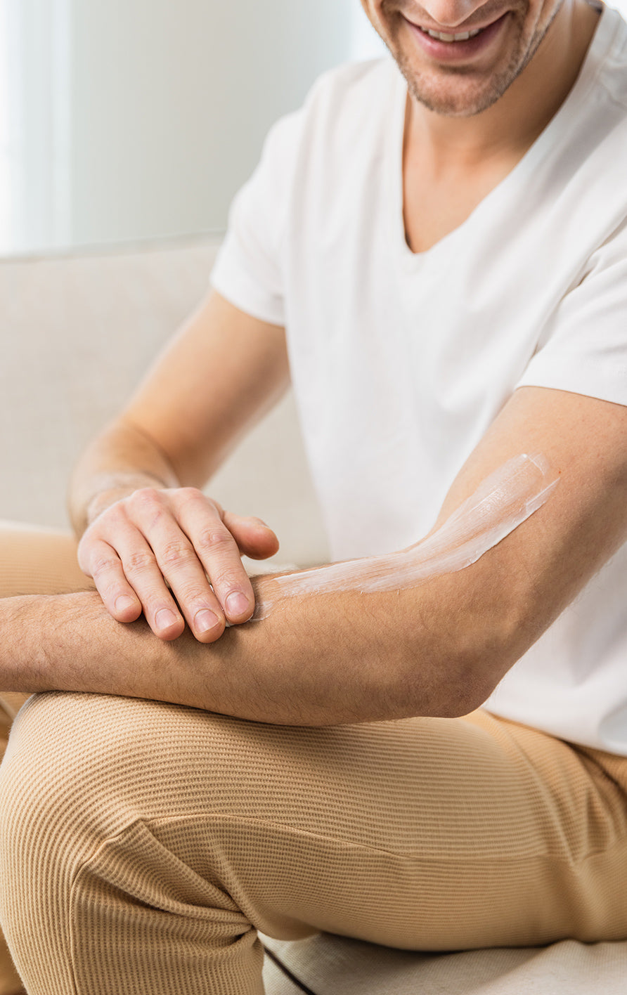a man rubbing moisturizer cream on to his arm