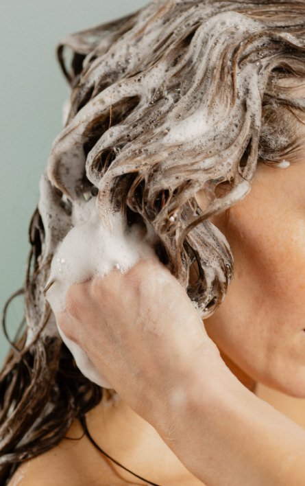 woman lathering shampoo in hair