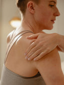 A person with short hair applies Rocky Mountain Soap Company Vanilla Coconut Daily Oat Lotion to their shoulder.