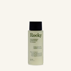 A bottle of Rocky Wild Kindness Conditioner in Rosemary Mint scent, featuring a pale yellow-green translucent bottle, dark green text, and a black cap, set against a solid off-white background.