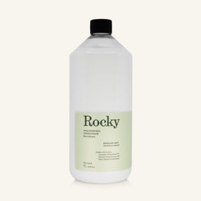 A 1L clear bottle of Rocky Wild Kindness Conditioner with a black cap and a pale green label, centered on a light cream background.