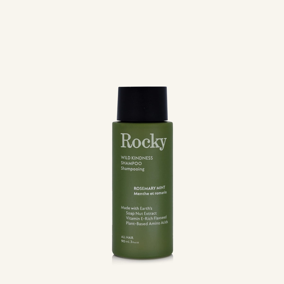 A 90ml bottle of Rocky Wild Kindness Shampoo in Rosemary Mint for normal hair, featuring an olive green bottle and a black cap, centered on a light cream background.