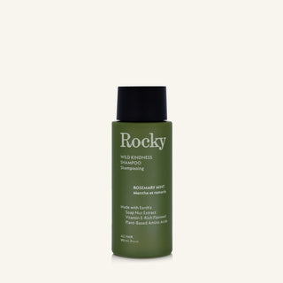 A 90ml bottle of Rocky Wild Kindness Shampoo in Rosemary Mint for normal hair, featuring an olive green bottle and a black cap, centered on a light cream background.