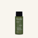 A 90ml bottle of Rocky Wild Kindness Shampoo in scent free for normal hair, featuring an olive green bottle and a black cap, centered on a light cream background.
