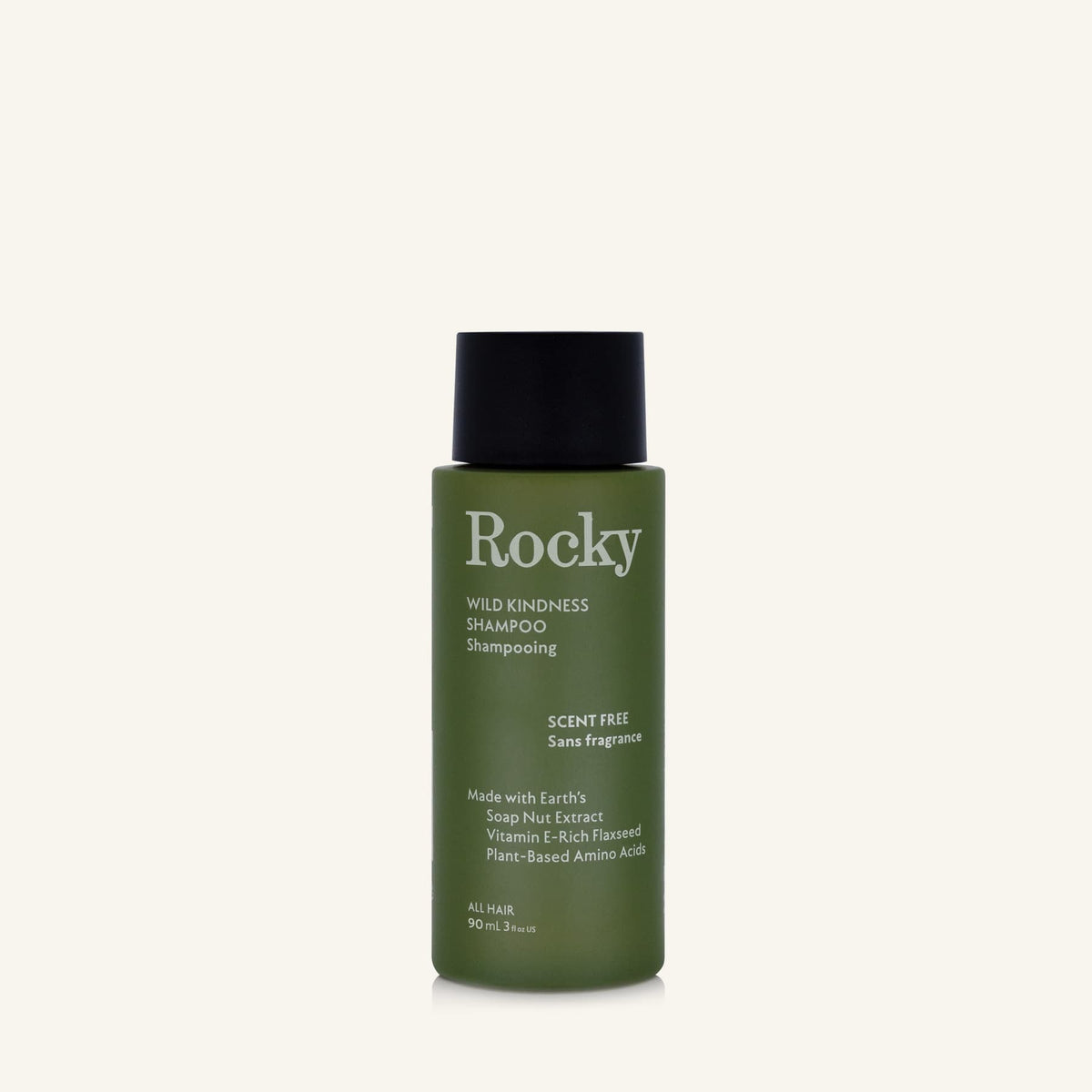 A 90ml bottle of Rocky Wild Kindness Shampoo in scent free for normal hair, featuring an olive green bottle and a black cap, centered on a light cream background.