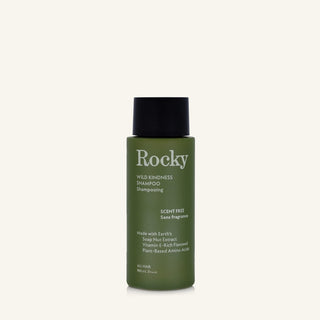 A 90ml bottle of Rocky Wild Kindness Shampoo in scent free for normal hair, featuring an olive green bottle and a black cap, centered on a light cream background.