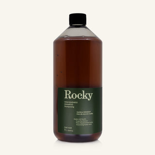 A 1L bottle of Rocky Wild Kindness Shampoo in Vanilla Coconut for fine hair, featuring an olive green bottle and a black cap, centered on a light cream background.