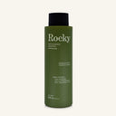 A 360ml bottle of Rocky Wild Kindness Shampoo in Rosemary Mint for normal hair, featuring an olive green bottle and a black cap, centered on a light cream background.
