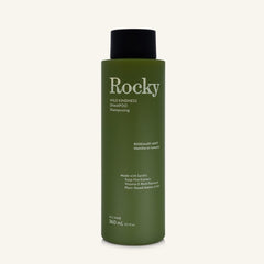 A 360ml bottle of Rocky Wild Kindness Shampoo in Rosemary Mint for normal hair, featuring an olive green bottle and a black cap, centered on a light cream background.