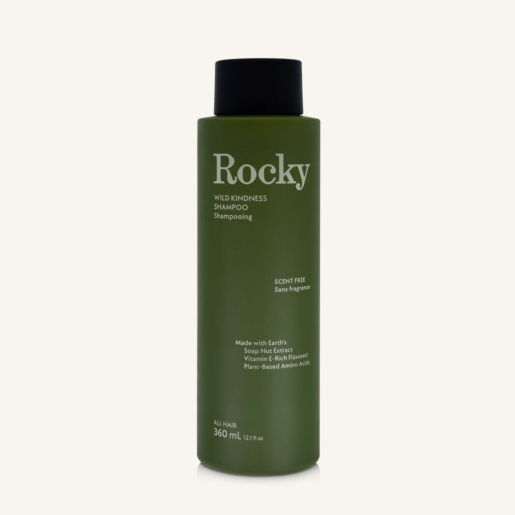 A 360ml bottle of Rocky Wild Kindness Shampoo in scent free for normal hair, featuring an olive green bottle and a black cap, centered on a light cream background.