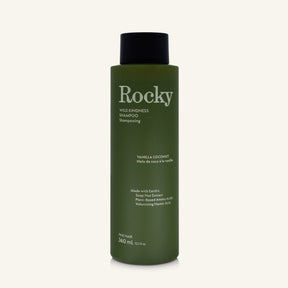A 360ml bottle of Rocky Wild Kindness Shampoo in Vanilla Coconut for fine hair, featuring an olive green bottle and a black cap, centered on a light cream background.