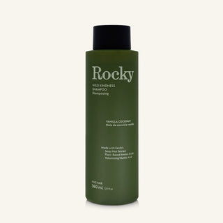 A 360ml bottle of Rocky Wild Kindness Shampoo in Vanilla Coconut for fine hair, featuring an olive green bottle and a black cap, centered on a light cream background.