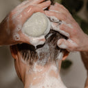 A person lathers a Rocky Mountain Soap Company Hair Bar: Shampoo and Conditioner Bundle into their wet hair.