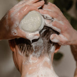 A person lathers a Rocky Mountain Soap Company Hair Bar: Shampoo and Conditioner Bundle into their wet hair.