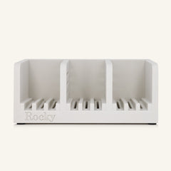 A white three-compartment soap holder with slotted bases and the name 'Rocky' embossed on the front, shown against a solid off-white background.