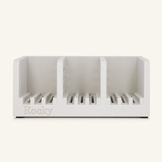 A white three-compartment soap holder with slotted bases and the name 'Rocky' embossed on the front, shown against a solid off-white background.