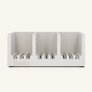 A white three-compartment soap holder with slotted bases and the name 'Rocky' embossed on the front, shown against a solid off-white background.