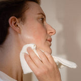 A person using a Relaxus Bamboo Face Cloth to gently wipe their face.