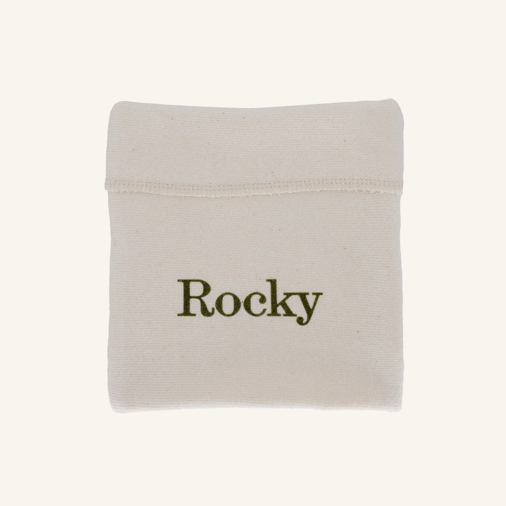 A small off-white fabric pouch with the name 'Rocky' printed in dark olive green text, shown on a plain light beige background.