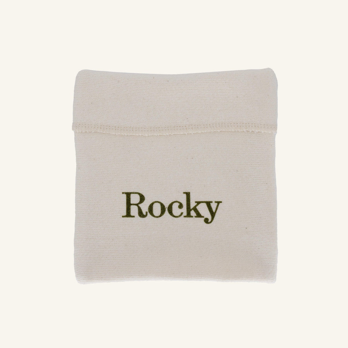 A small off-white fabric pouch with the name 'Rocky' printed in dark olive green text, shown on a plain light beige background.