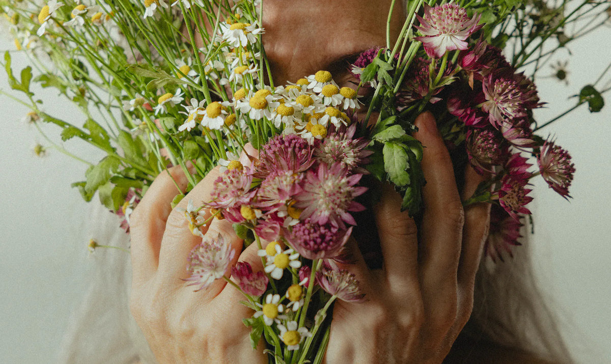 Karina Birch holding a bundle of chamomile and astrantia against her face