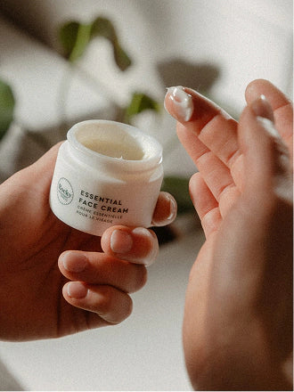 Fingers dipping into an open jar of Essential Face Cream