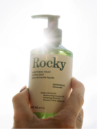 A hand holding a pump bottle of Everything Wash in Lemongrass
